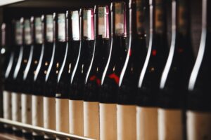 Row,Of,Red,Wine,Bottles,Lined,Up,On,Wooden,Shelves